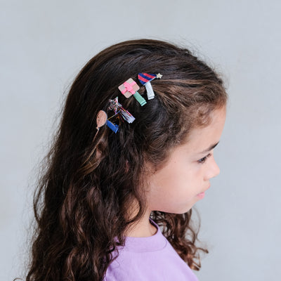girl wearing birthday themed mini hair clips against a white background
