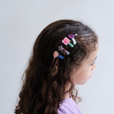 girl wearing birthday themed mini hair clips against a white background