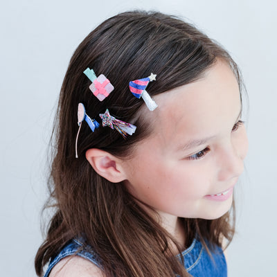 girl wearing birthday themed mini hair clips against a white background
