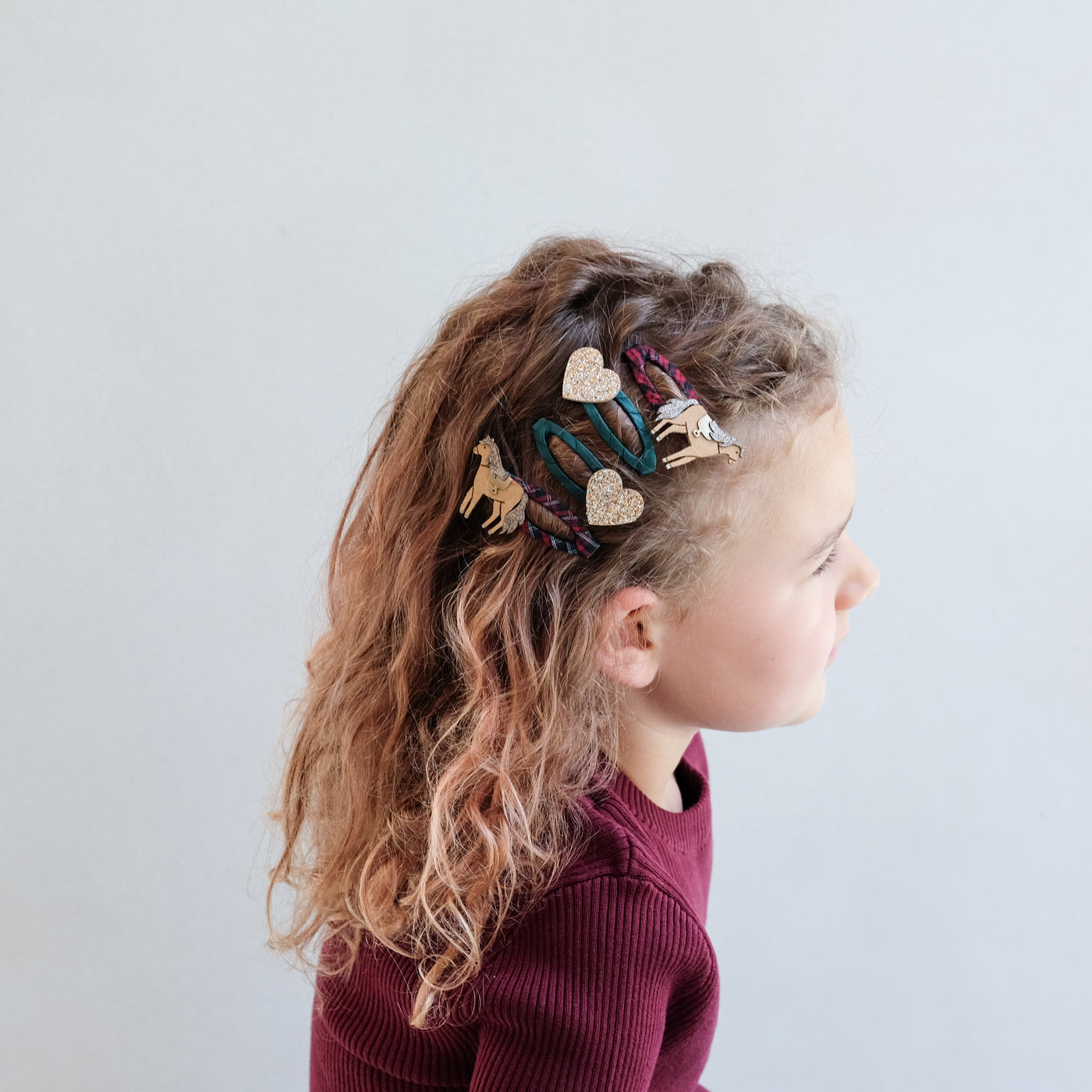 girl wearing horsey clic clacs hair clips in her hair against a white background