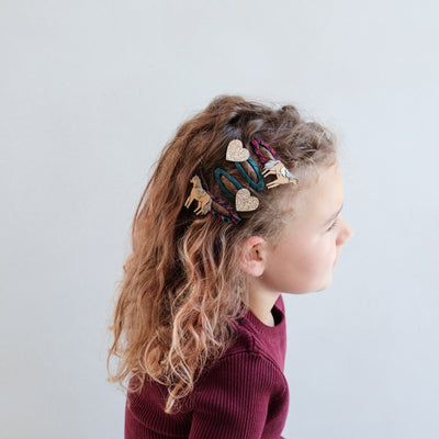 girl wearing horsey clic clacs hair clips in her hair against a white background