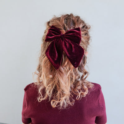 girl wearing red tartan agnes bow set in her hair against a white background