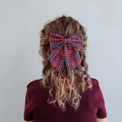 girl wearing red tartan agnes bow set in her hair against a white background