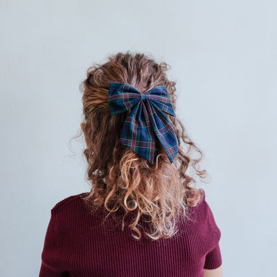 girl wearing tartan agnes bow set in green in her hair against a white background