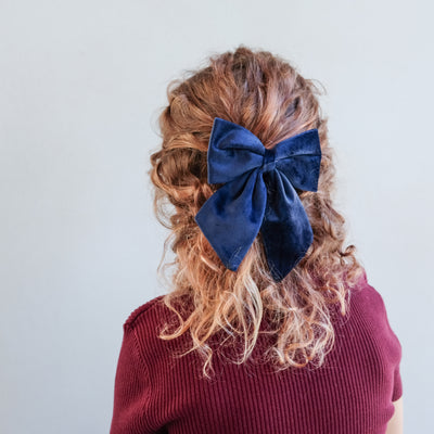 girl wearing stripe agnes bow set in her hair against a white background