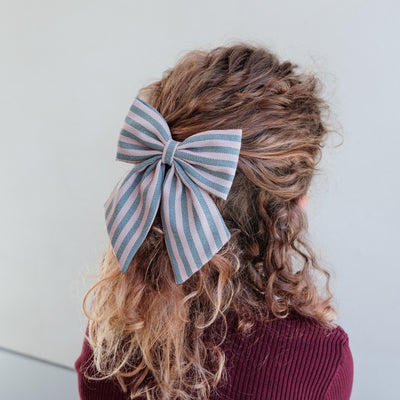 girl wearing stripe agnes bow set in her hair against a white background