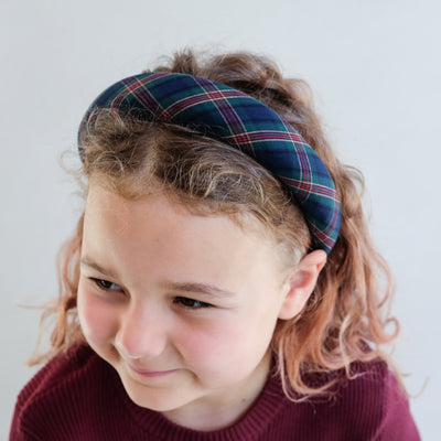 Child wearing a plaid padded headband with a plain background
