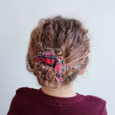 girl wearing giant tartan scrunchie in hair against a white background