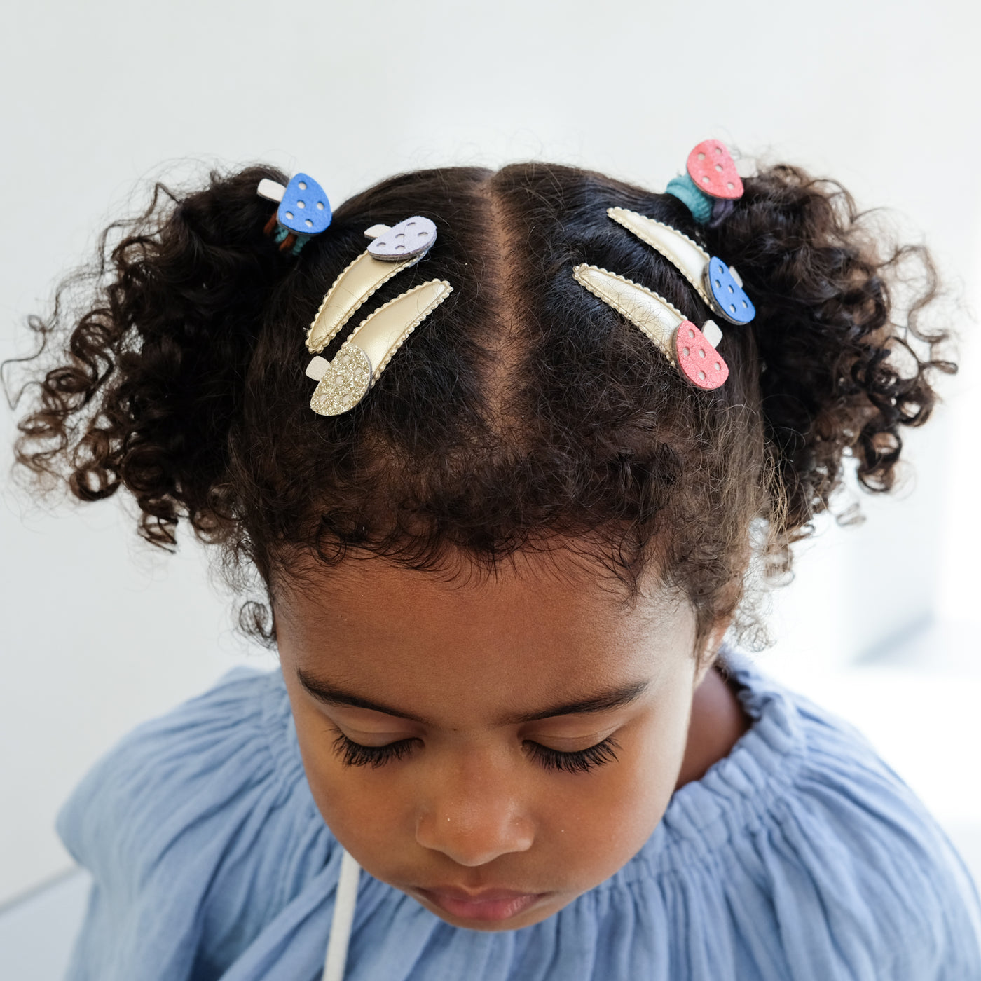 Girl with styled hair featuring colourful girls hair clips and hair ties on a light background