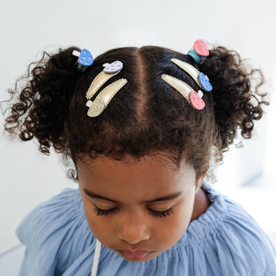 Girl with styled hair featuring colourful girls hair clips and hair ties on a light background