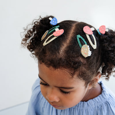 Child with colourful girls hair clips in their hair against a white background