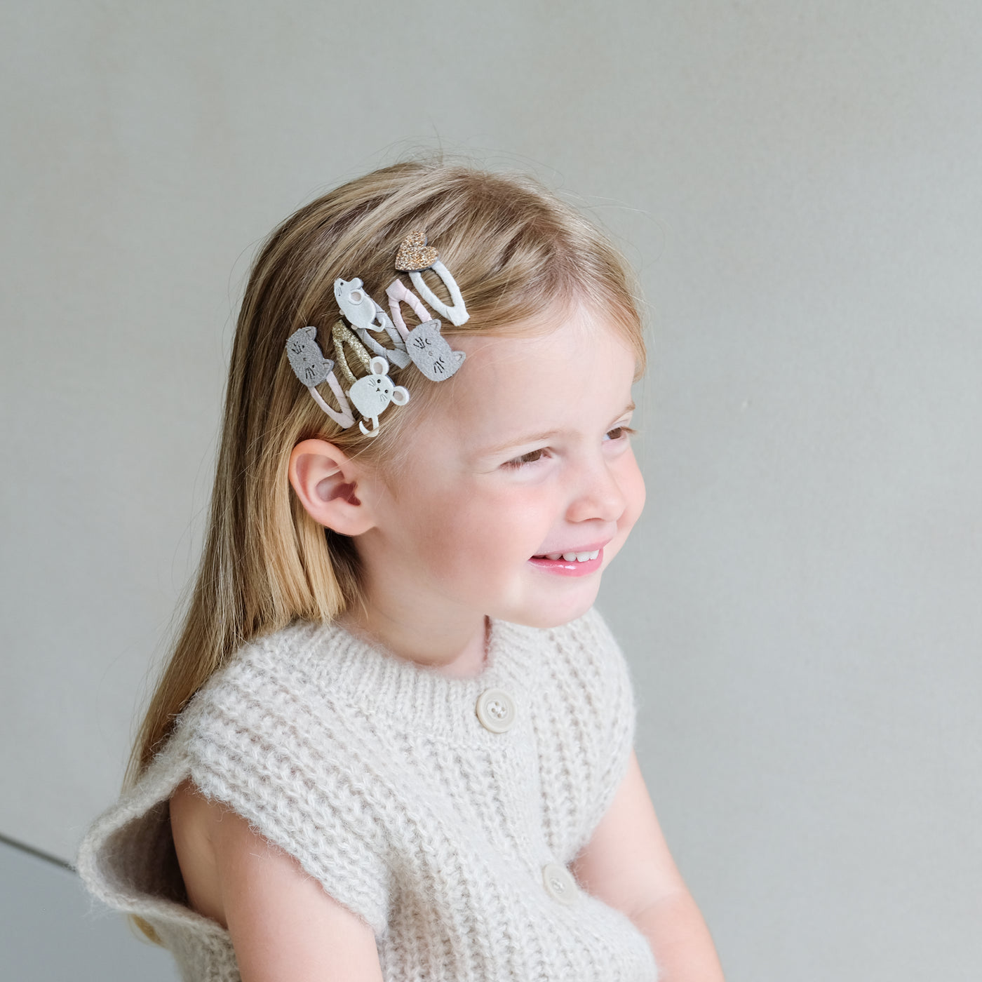 young girl wearing cat & mouse hair clips in her hair against a plain background