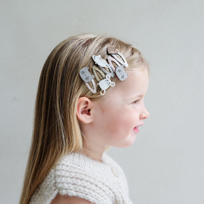 young girl wearing cat & mouse hair clips in her hair against a plain background