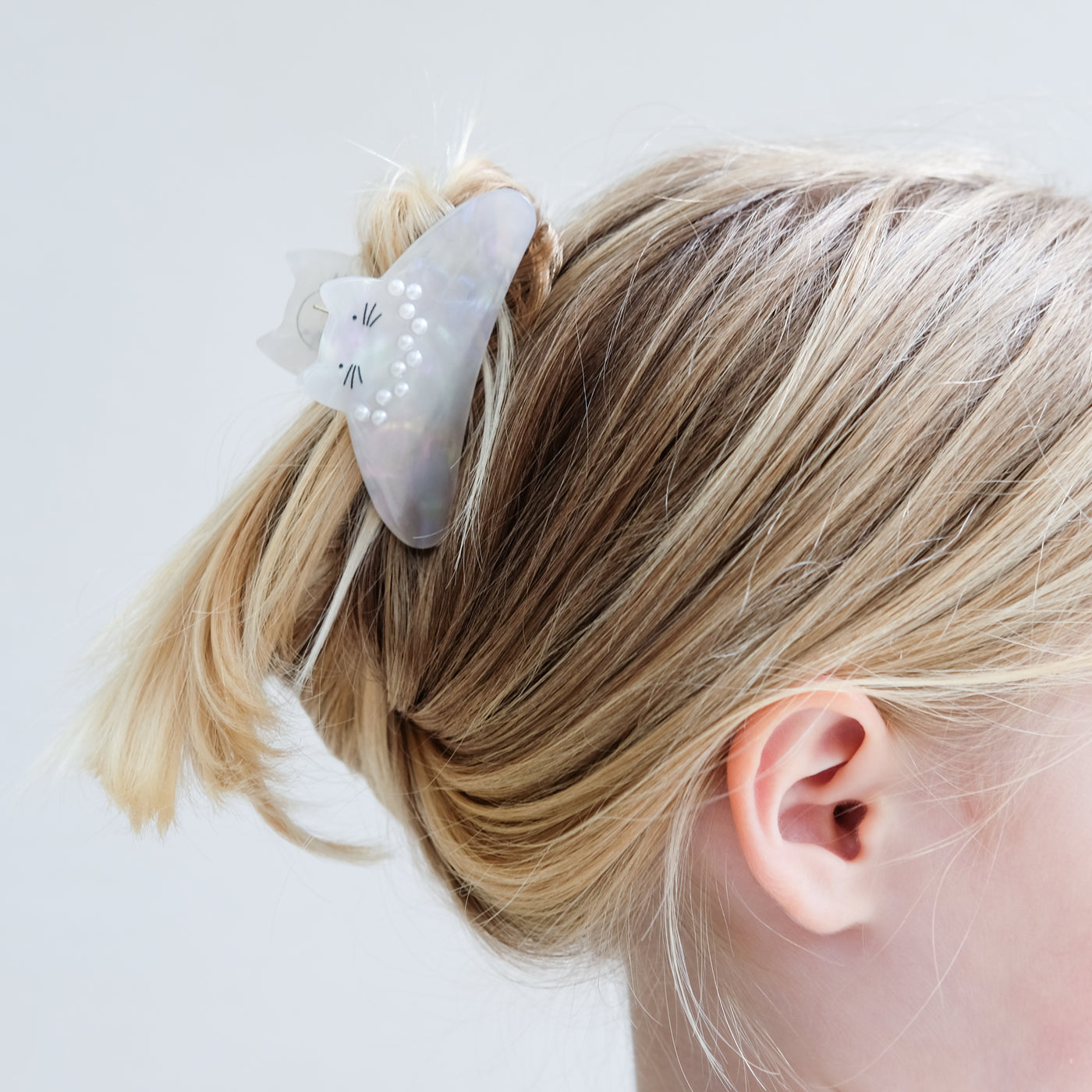 girl wearing pearly kitty claw clip in her hair against a white background
