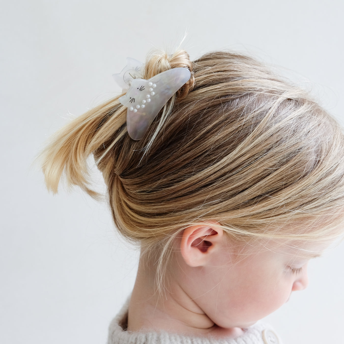 girl wearing pearly kitty claw clip in her hair against a white background
