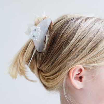 girl wearing pearly kitty claw clip in her hair against a white background