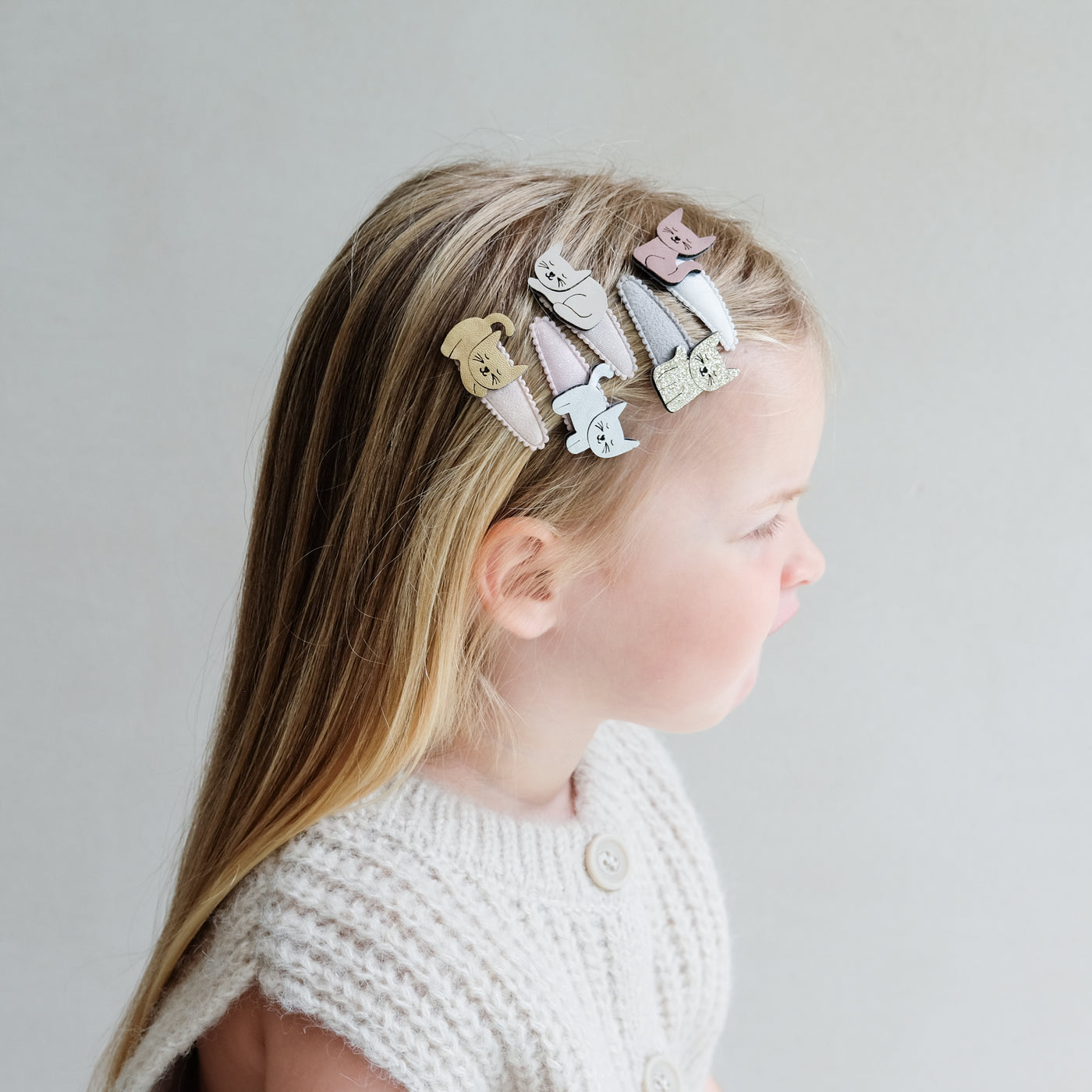 young girl wearing Kitty cat clic clac hair clips in her hair against a plain background