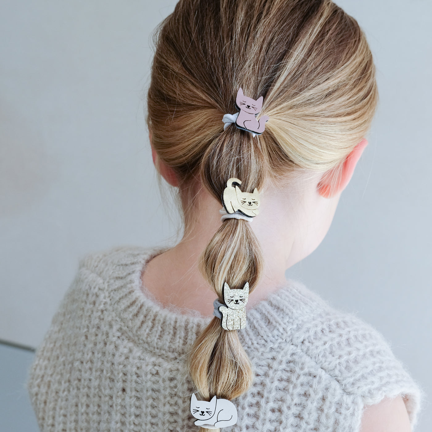 girl wearing kitty cat ponies in her hair against a white background