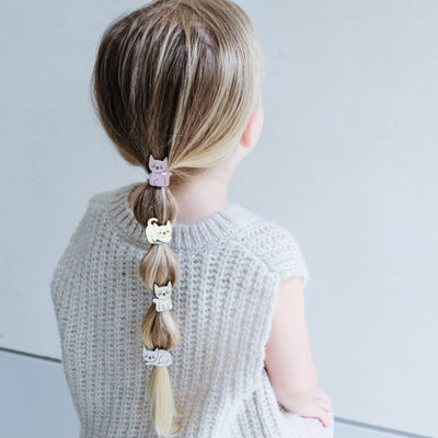 girl wearing kitty cat ponies in her hair against a white background
