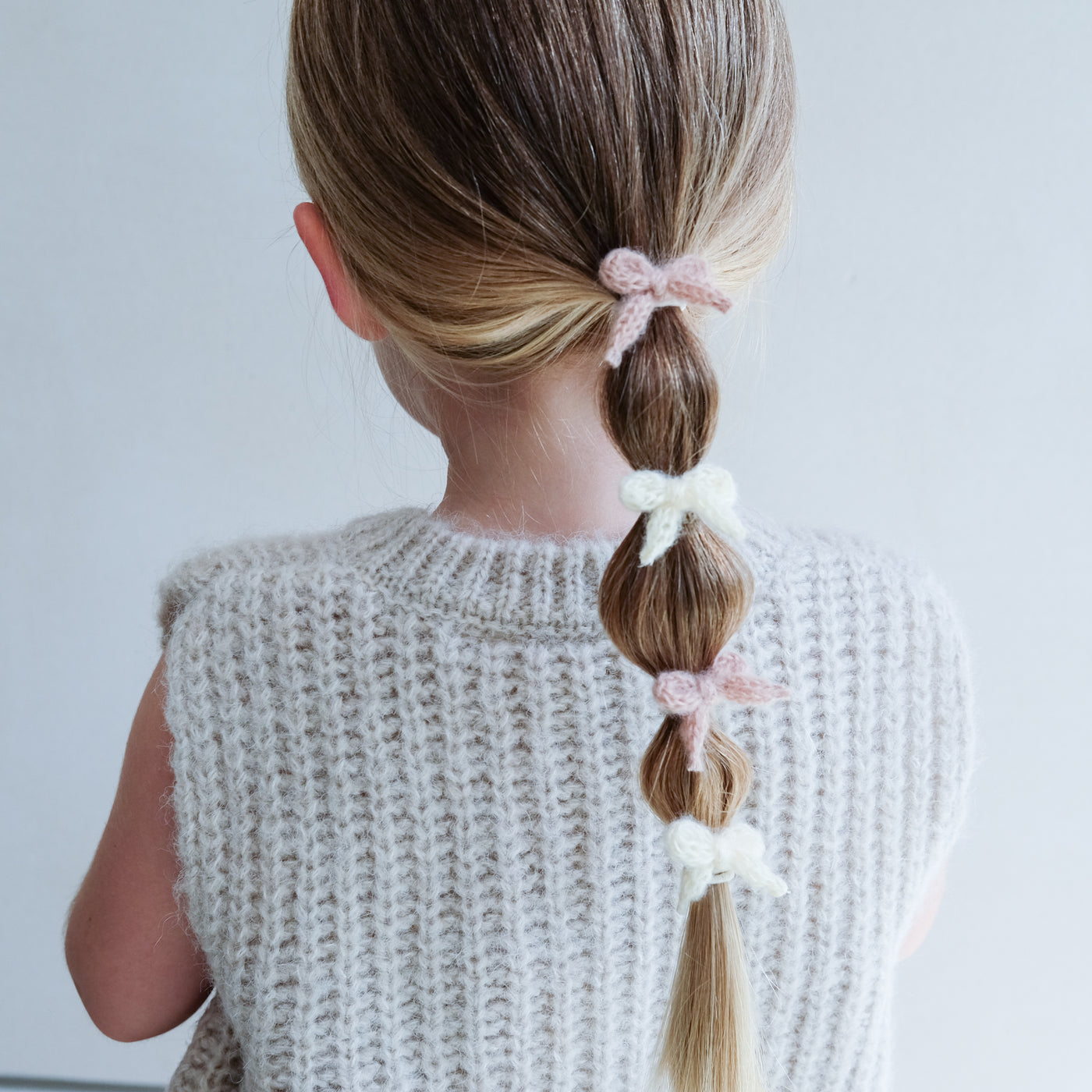 girl wearing Granny knitted bow mini ponies in her hair against a white background