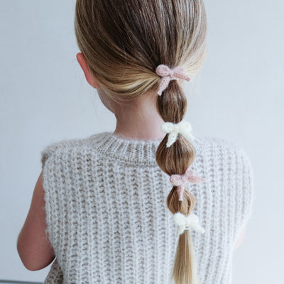 girl wearing Granny knitted bow mini ponies in her hair against a white background