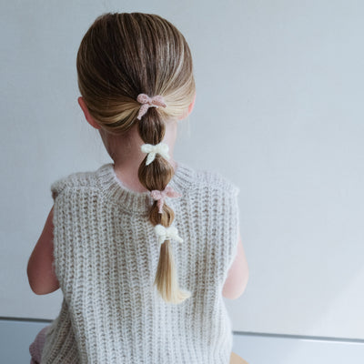 girl wearing Granny knitted bow mini ponies in her hair against a white background