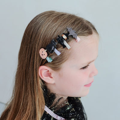 girl wearing halloween mini clips in her hair against a white background