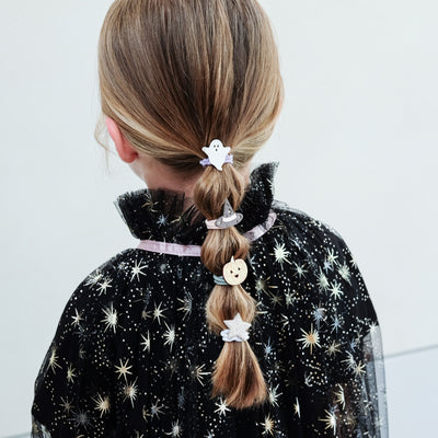 girl wearing halloween ponies in her hair against a white background