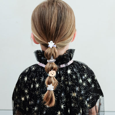 girl wearing halloween ponies in her hair against a white background