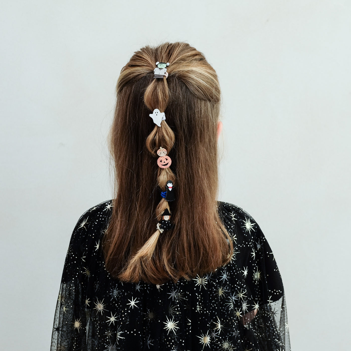 girl wearing monster mini ponies in her hair against a white background