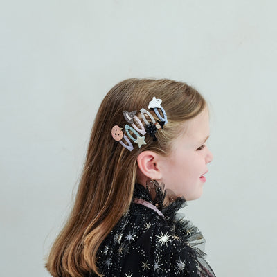 girl wearing halloween mini clic clacs in her hair against a plain background