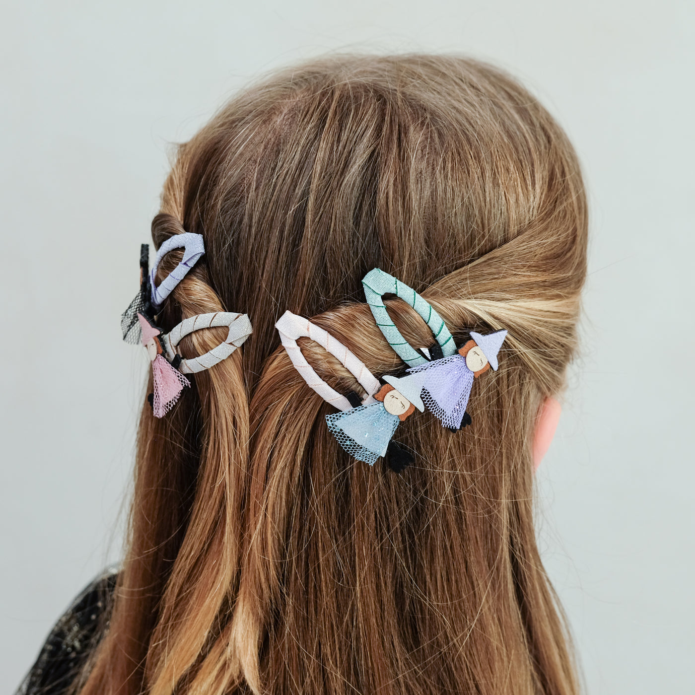 girl wearing witch friends halloween hair clips in her hair against a plain background