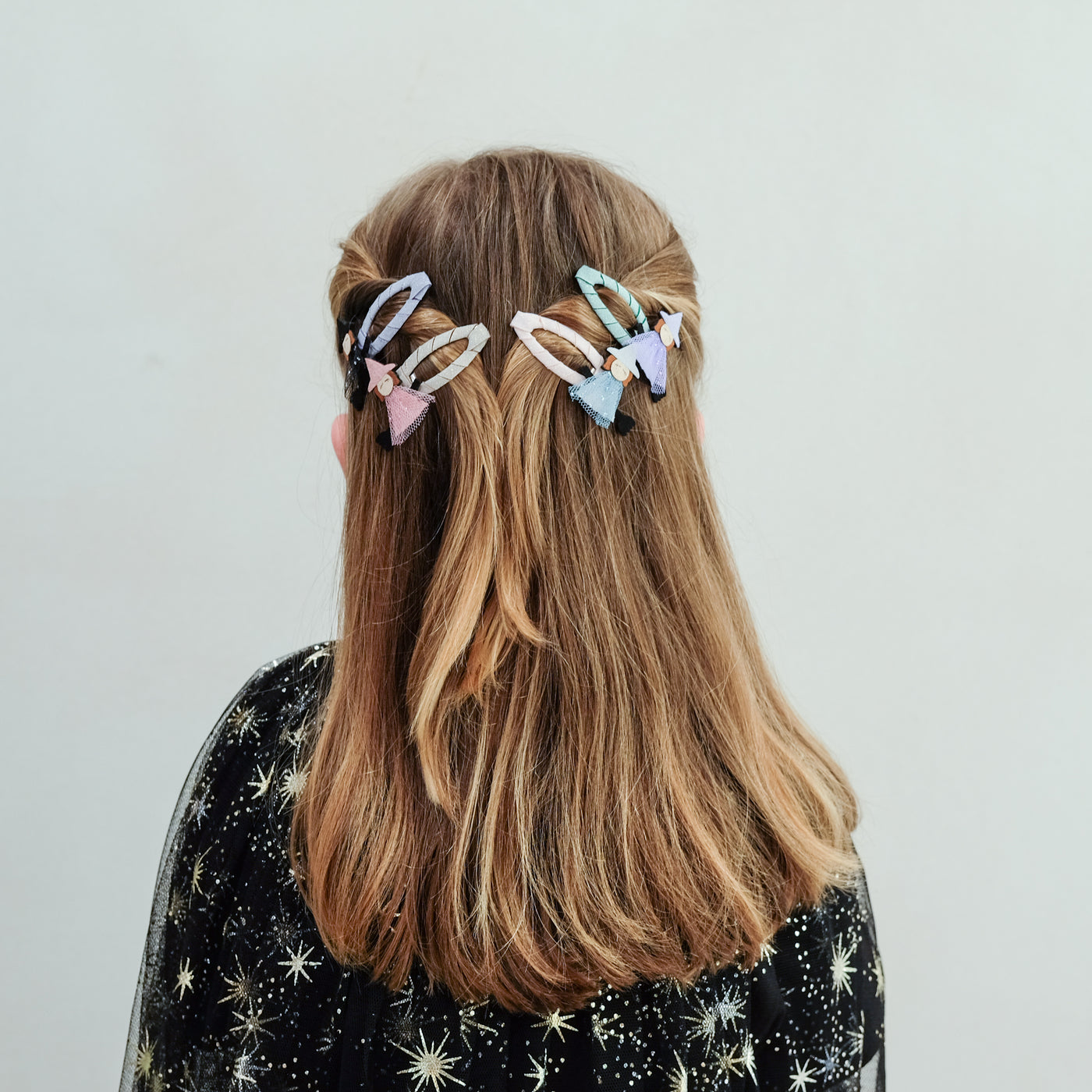 girl wearing witch friends hair clips in her hair against a plain background