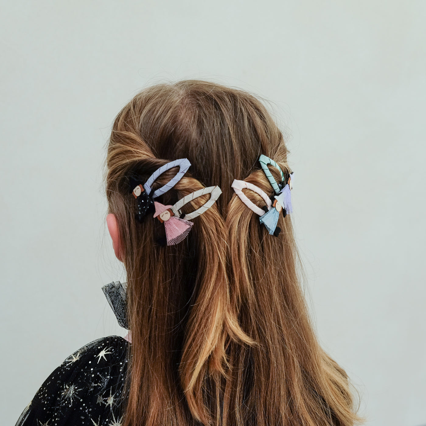 girl wearing witch friends halloween hair clips in her hair against a plain background