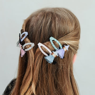 girl wearing witch friends halloween hair clips in her hair against a plain background