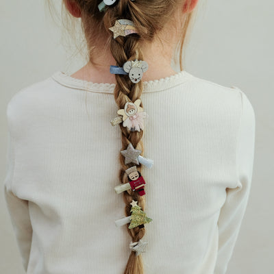girl wearing nutcracker mini hair clips styled in her hair against a plain background