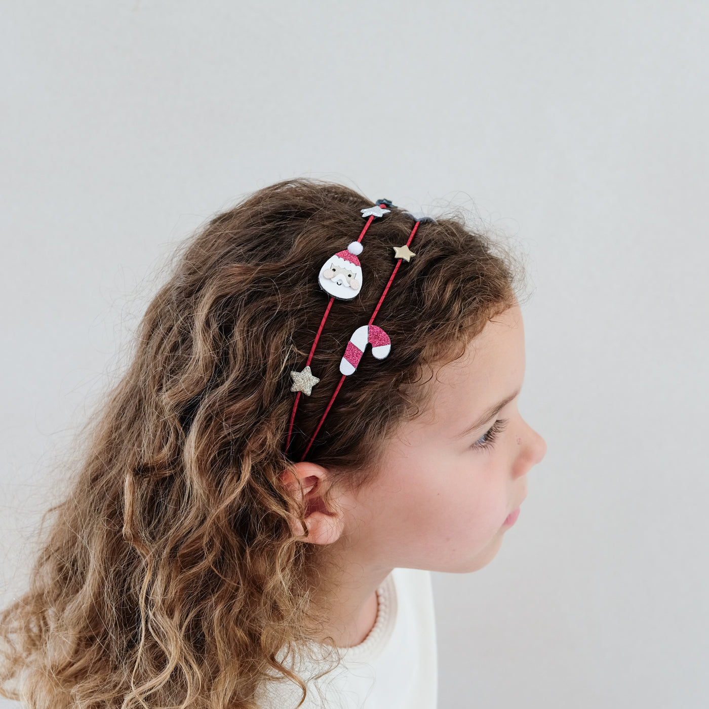 Child with decorative Christmas headband on a plain background