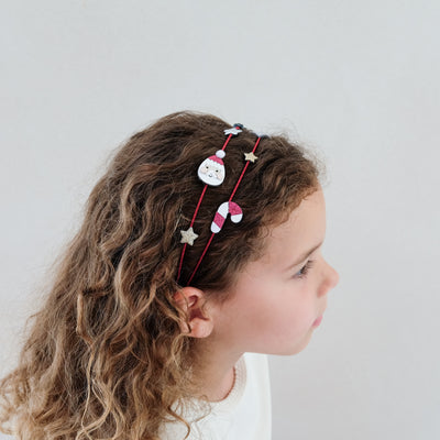 Child with decorative Christmas headband on a plain background
