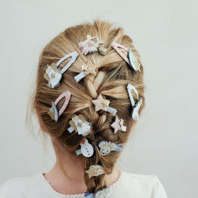 child with hair in a braid hair style wearing angel mini hair clips in her hair against a plain background