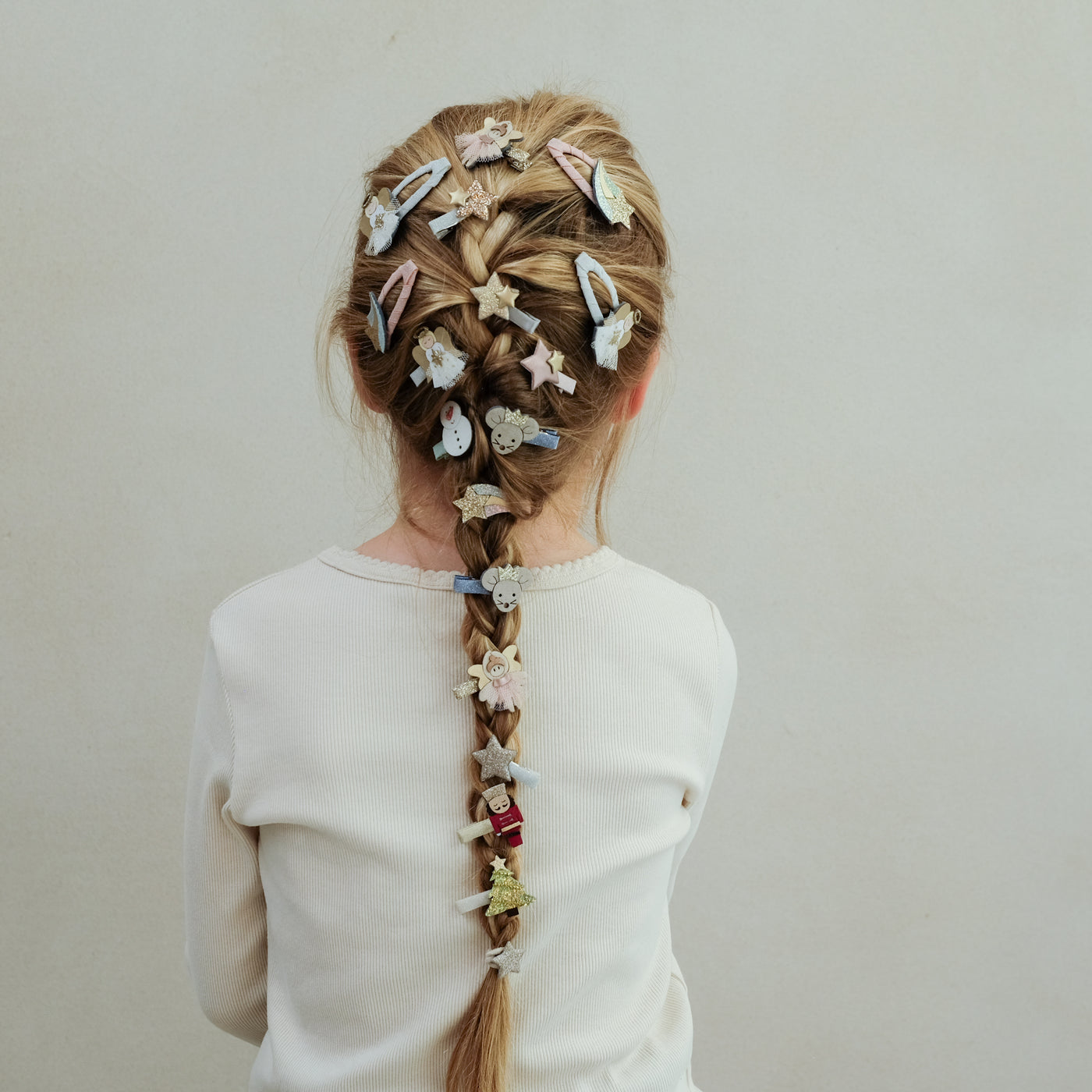 girl wearing christmas themes hair clips in her braided hair against a white background