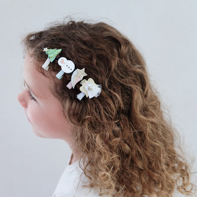 child with curly hear wearing angel mini hair clips in her hair against a plain background