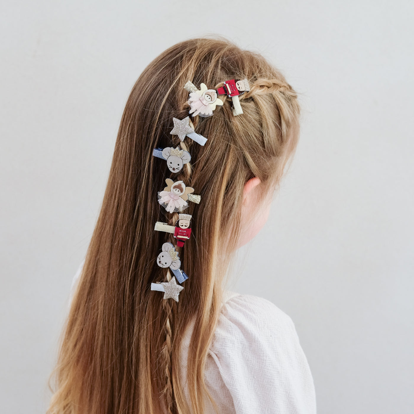 girl wearing nutcracker mini hair clips styled in her hair against a plain background