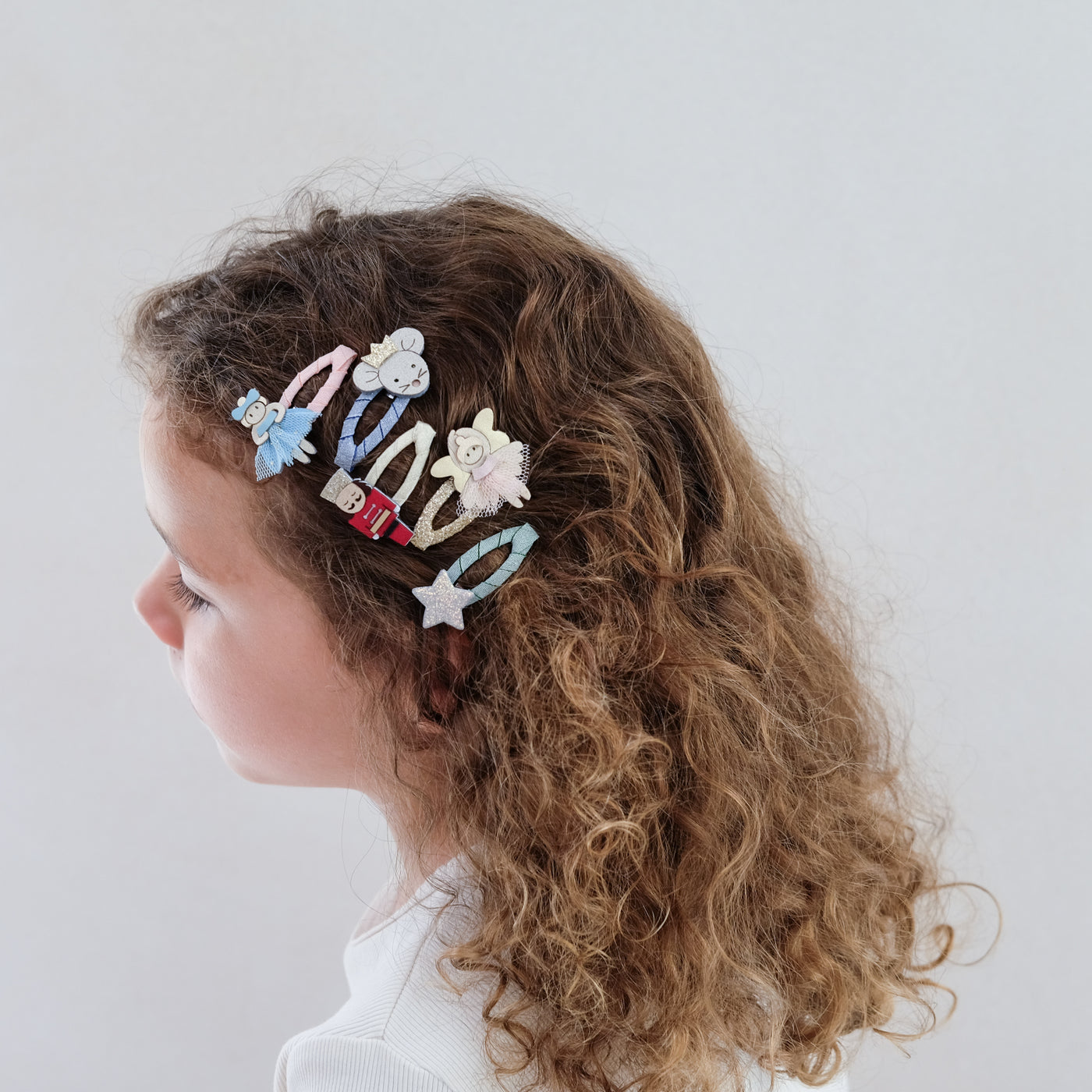 girl wearing nutcracker mini hair clips styled in her hair against a plain background
