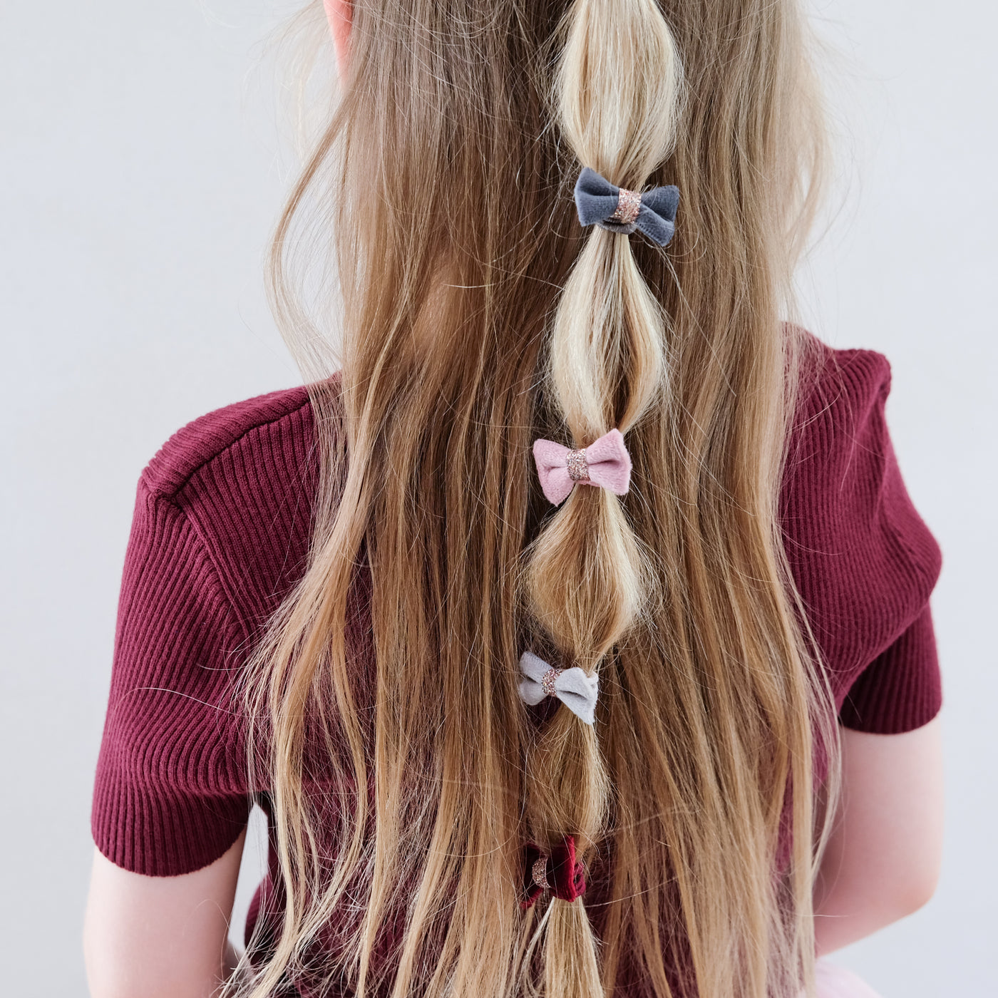 girl wearing Christmas velvet bow ponies in her hair against a white background
