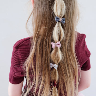 girl wearing Christmas velvet bow ponies in her hair against a white background