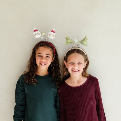 Two children wearing festive bopper headbands with Christmas details against a plain background.