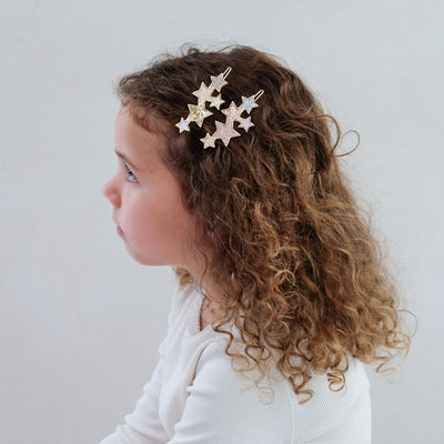 girl wearing starry snap grips in her hair against a white background