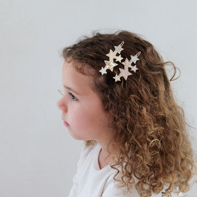girl wearing starry snap grips in her hair against a white background