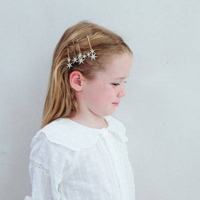 girl wearing super sparkle hair grips hair accessories in her hair against a white background