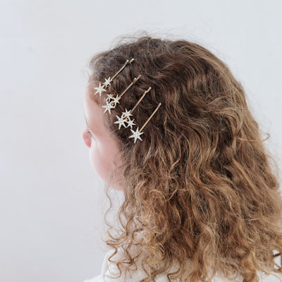 girl wearing super sparkle hair grips hair accessories in her hair against a white background
